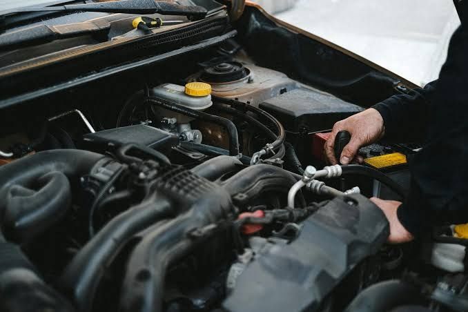 Dan working on a vehicle engine under the hood in his workshop
