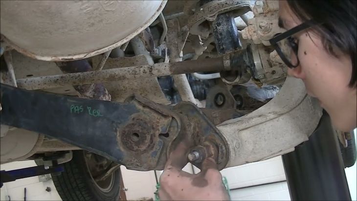 Underbody view of a CR-V suspension trailing arm and links being inspected for play