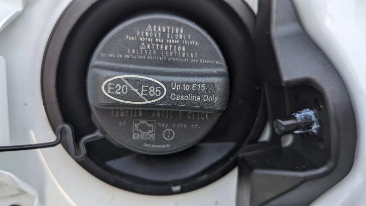 Toyota Camry gas cap door opened showing regular unleaded fuel sticker